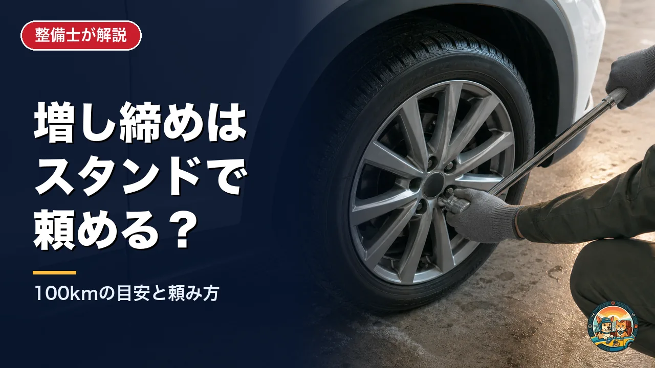 ガソリンスタンドの作業場で、整備士が片手でトルクレンチの頭をホイールナットに押さえ、もう片方の手で柄を握って冬タイヤのナットを締めている