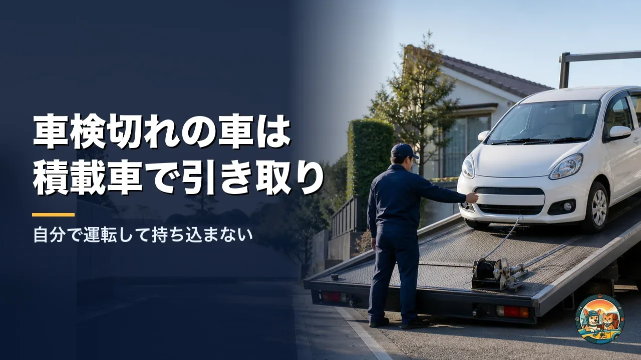 住宅街で白いコンパクトカーを積載車の荷台に載せ、作業員がウインチのワイヤーを付けて引き取っている